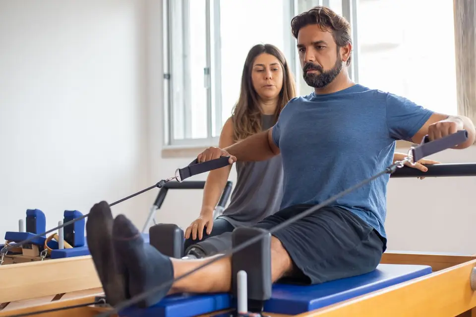 Fisioterapeuta orientando paciente em exercício de pilates no reformer
